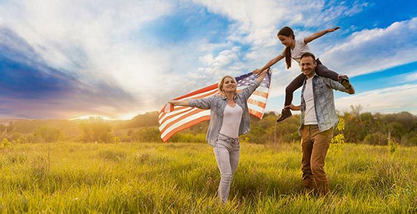 family in a field holding an united states flag